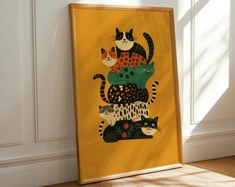 May include: A framed art print depicting a tower of six stylised cats in different colours and patterns. The cats are stacked on a mustard yellow background. The artwork is presented in a wooden frame.