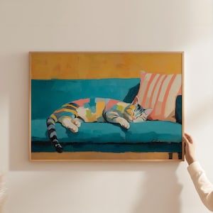 May include: A framed art print depicts a colorful cat napping on a teal sofa. The cat's fur is a patchwork of colors, and a striped pillow rests behind it. The background is a blend of yellow and teal.