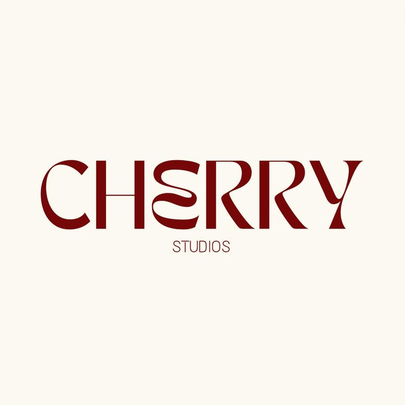 Op de afbeelding: Het logo voor Cherry Studios toont het woord "CHERRY" in een bordeauxrode, gestileerde letter, met "STUDIOS" in een kleinere letter eronder. De achtergrond is lichtcr&egrave;me van kleur.