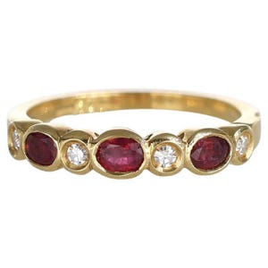 May include: A gold band ring featuring oval-cut red gemstones and small, round, clear gemstones. The ring has a classic design with the gemstones set in individual bezels. The ring is a jewelry item.