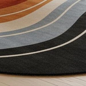 May include: A round rug with a wave design in shades of orange, tan, gray, and black. The rug has a soft texture and a modern aesthetic, suitable for living rooms or bedrooms. The rug's diameter is approximately 60 inches.