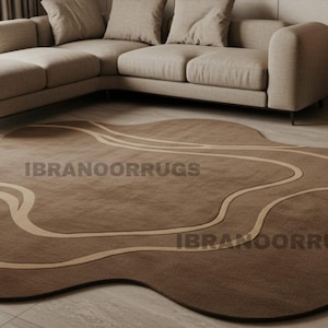 May include: A brown, abstract-shaped rug with a lighter brown wavy design. The rug is on a tiled floor in front of a beige sectional sofa. The text "IBRANOORRUGS" is printed on the rug.