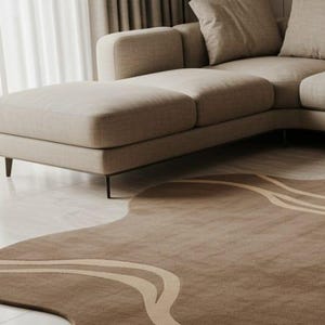 May include: A modern living room scene featuring a beige sectional sofa and a uniquely shaped brown rug. The rug has a wavy design with lighter beige stripes. The room is illuminated by natural light from a nearby window.