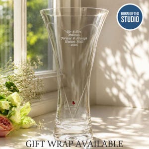 May include: A clear glass vase with a flared rim and a tapered base, featuring an etched heart outline and the engraved text Mr & Mrs Pointon, Forever & Always, Weston Hall, 2026, accented by a single small red crystal embedded in the glass.