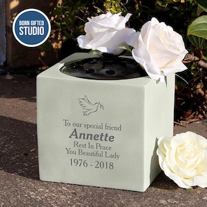 May include: A pale green square memorial vase with white roses. The vase has a black flower insert and the inscription "To our special friend Annette Rest In Peace You Beautiful Lady 1976-2018". The logo "BORN GIFTED STUDIO" is in the upper left corner.