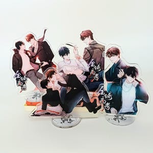 Peut inclure: Présentoirs en acrylique avec des illustrations de style anime de personnages masculins dans diverses poses. Les personnages sont représentés dans différentes tenues, décontractées ou formelles. Les présentoirs ont des bases transparentes et du texte chinois.