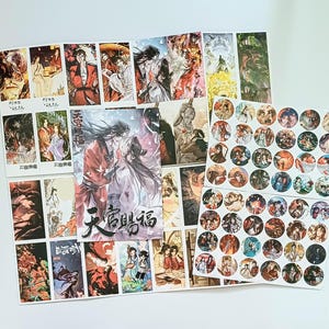 May include: A selection of printed art featuring illustrations of characters in various poses and settings. The art includes rectangular prints and round stickers with detailed character designs, in a variety of colours. The prints have Chinese characters.