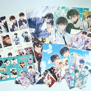 May include: A selection of anime-style art prints depicting male characters in diverse scenarios. The prints display illustrations of romantic scenes and character portraits. The colour scheme includes blues, whites, and skin tones, creating a visually appealing collection.