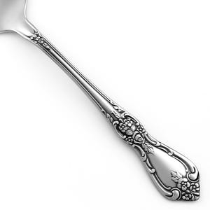 May include: A silver-toned metal spoon handle featuring an intricate embossed floral pattern. The design includes detailed clusters of small flowers and leaves along the stem and at the rounded end, with a smooth, polished finish throughout.