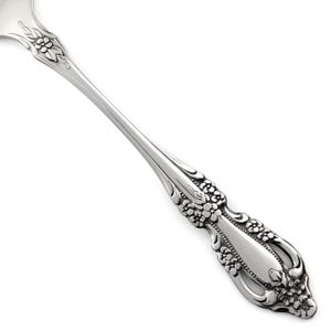 May include: A silver-toned metal spoon handle featuring an intricate embossed floral pattern. The design includes a cluster of small flowers at the neck and a larger, detailed floral motif at the base of the handle, with a smooth central panel.