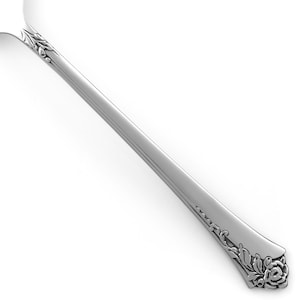 May include: A silver-toned metal spoon handle featuring a polished finish and intricate embossed floral detailing at the neck and the base. The design includes sculpted leaves and a rose motif at the bottom edge of the handle.