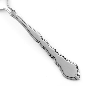 May include: A silver-toned metal spoon handle featuring a smooth, matte-finished center panel bordered by a decorative, scalloped edge. The handle tapers toward the neck and widens at the base, showcasing a consistent metallic sheen throughout.