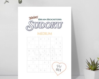Op de afbeelding: Een wit Sudoku-puzzelboek met de tekst "30 day Brain Boosters Sudoku Medium". Het puzzelrooster is zichtbaar, met enkele getallen ingevuld. Een hartvormige afbeelding met "Vol 011" staat in de rechter benedenhoek.