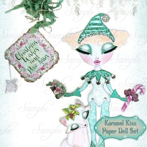 May include: A digital illustration of a Christmas-themed paper doll set. The set includes a doll in an elf costume, a deer, and a tag with the text "Christmas Wishes and Pixie Kisses". The set is titled "Karamel Kiss Paper Doll Set".