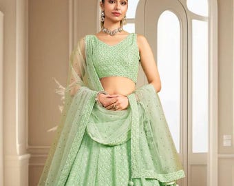 Op de afbeelding: Een lichtgroene lehenga choli set. De outfit heeft ingewikkelde borduursels en een bijpassende dupatta. De rok is lang en de top is een crop-stijl. De set is geschikt voor speciale gelegenheden.