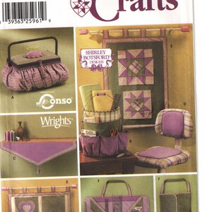 May include: Simplicity Crafts sewing pattern featuring various quilted projects. The image showcases a sewing box, a wall hanging, a chair, a tote bag, and other craft items. The color palette includes shades of purple, green, and beige.