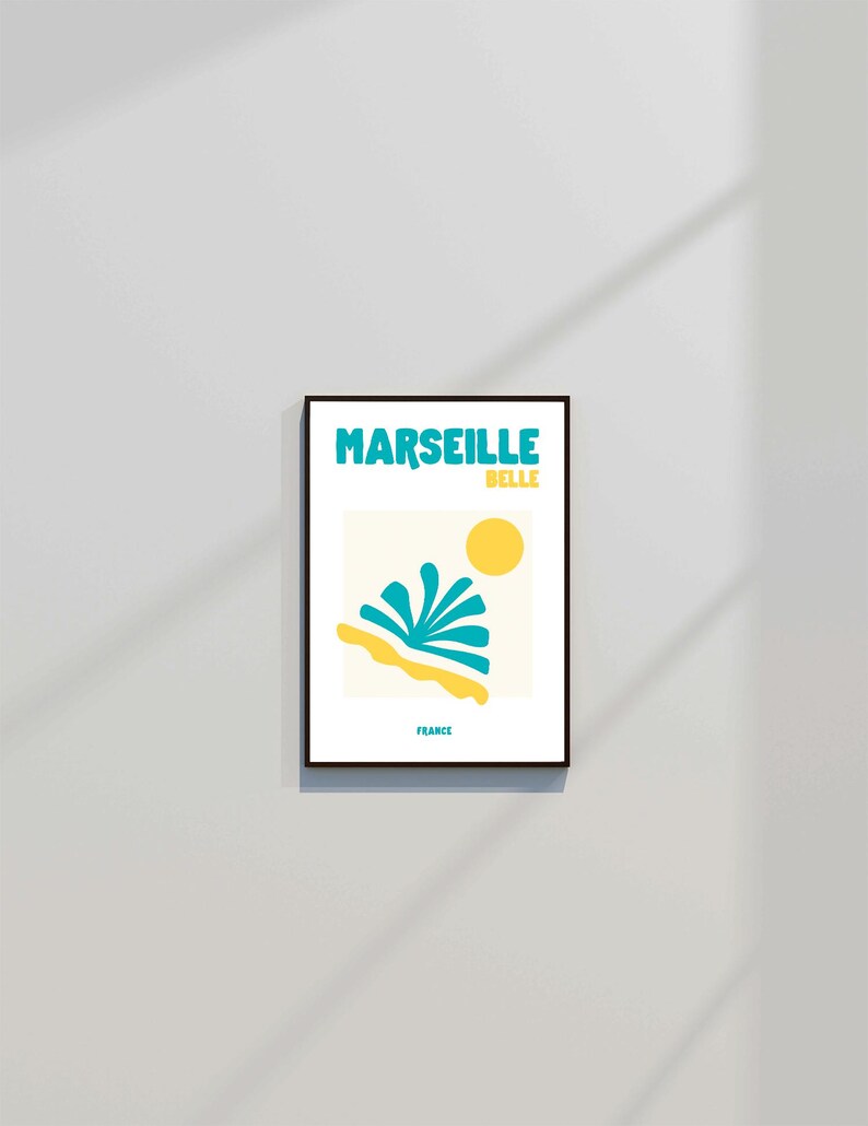 May include: A framed art print featuring the words "MARSEILLE BELLE" in turquoise above a yellow sun and abstract turquoise and yellow shapes. The word "FRANCE" is printed below the image.