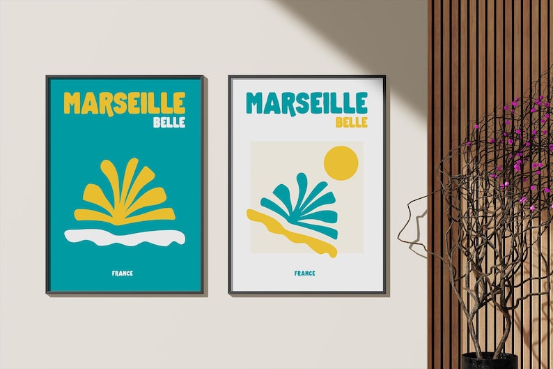 May include: Two framed art prints with the words "Marseille Belle" in yellow and teal. One print has a teal background with a yellow and white design. The other has a white background with a teal, yellow, and orange design.