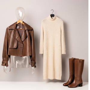 May include: A brown leather jacket, a cream-colored cable-knit dress, and brown knee-high boots. The jacket is cropped with a wide collar and button details. The dress has a turtleneck. The boots have a block heel.