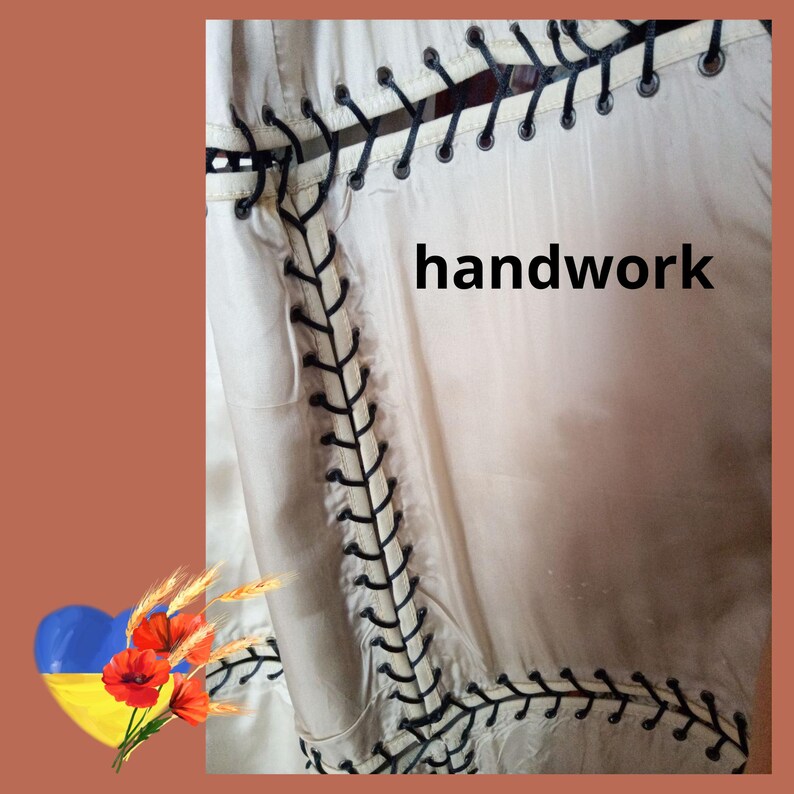 May include: Cream-coloured fabric with black decorative stitching and the word "handwork" in black. The stitching creates a border and vertical lines, adding a unique design element to the textile.