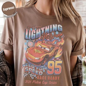 May include: Espresso-colored t-shirt featuring a graphic of Lightning McQueen from the movie Cars. The design includes the text "Street Legend Lightning McQueen", "Need for Speed", and "95". The shirt is part of the 2026 Piston Cup Series.