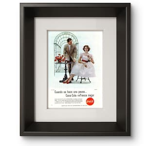 Puede incluir: Un anuncio publicitario vintage de Coca-Cola en un marco negro. La imagen muestra a una persona con traje beige y a otra con vestido blanco con detalles rojos sentadas en una mesa pequeña. El texto dice: Cuando se hace una pausa... Coca-Cola refresca mejor.