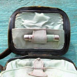 May include: A black leather case with a green and silver pocket flashlight inside. The case has a flap that closes with a snap.