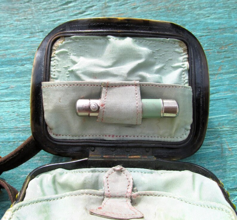 May include: A black leather case with a green and silver pocket flashlight inside. The case has a flap that closes with a snap.
