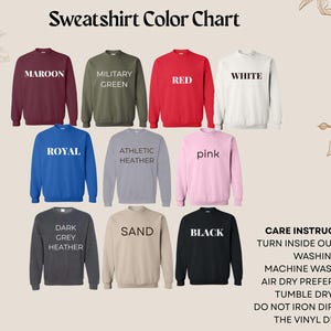May include: A sweatshirt color chart displaying nine crewneck sweatshirts in maroon, military green, red, white, royal blue, athletic heather, pink, dark grey heather, sand, and black, with care instructions text on the bottom right corner.