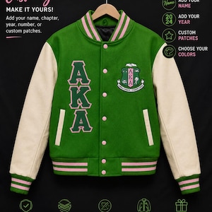 May include: A green varsity jacket with cream-colored sleeves, featuring pink and green striped ribbed trim at the collar, cuffs, and hem. The front displays the letters AKA in green with pink outlines and a crest patch with the text AKA.
