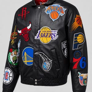 Puede incluir: Una chaqueta universitaria de cuero negro con numerosos parches bordados coloridos de varios logotipos de equipos de baloncesto profesionales, incluidos los Lakers, Knicks, Bulls y Celtics, con forro rojo y cierre frontal de botones a presión.