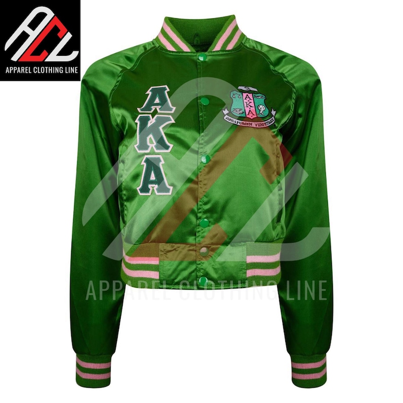 May include: A green satin cropped bomber varsity jacket featuring pink striped ribbed trim on the collar, cuffs, and hem. The front displays the letters AKA in white with green outlines, a circular crest logo, and a row of green snap buttons down the center.