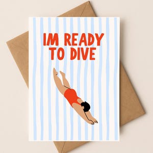 Peut inclure: Carte de vœux avec le texte "I'M READY TO DIVE" en rouge. La carte présente une illustration d'une personne plongeant dans l'eau, vêtue d'un maillot de bain rouge. Le fond est composé de rayures verticales bleues et blanches. La carte est posée sur une enveloppe marron.