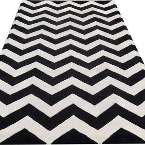 May include: A rectangular rug with a bold chevron pattern in black and white. The zig-zag design creates a striking visual effect, suitable for various interior styles. The rug's texture appears soft and inviting.