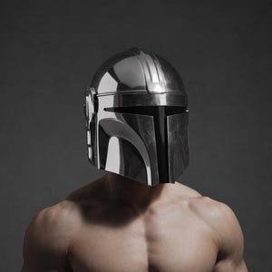May include: A chrome-colored Mandalorian helmet is worn by a person with a muscular physique. The helmet has a distinctive T-shaped visor and a ridged top. The person is shirtless, with defined abdominal muscles and toned arms.