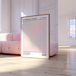 Op de afbeelding: Een ingelijste kunstdruk getiteld "Eternal Light" uit de Aura Collection. Het kunstwerk heeft een zacht, gradiënt kleurenschema van roze en wit. De print bevat het nummer "1111" en een kort citaat. Het frame is goudkleurig.