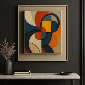 May include: Abstract art print in a gold frame. The artwork features a geometric design with shapes in red, orange, yellow, blue, and black. The framed art is displayed on a marble-topped table with a vase and books.