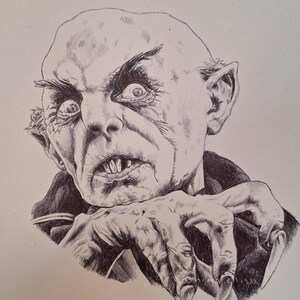 May include: A detailed pen and ink drawing of a bald, grotesque creature with sharp teeth and long, claw-like nails. The creature's face is contorted in a menacing expression, with intense eyes and prominent ears. The artwork is done in black and white.