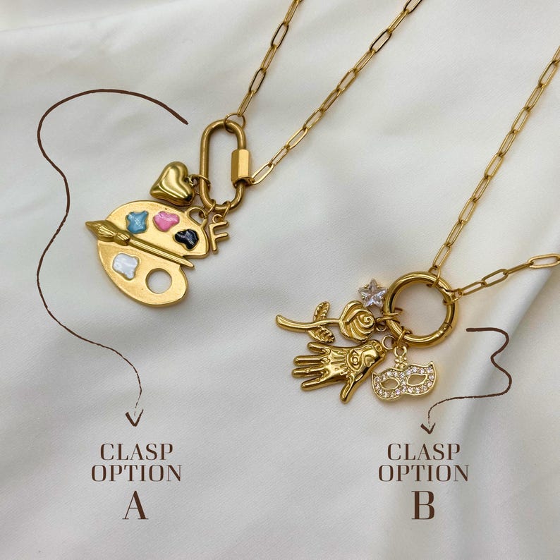 May include: Two gold-colored necklaces with different charm options. One features a painter's palette with colorful paint, a heart, and the letter "F". The other has a rose, hand, mask, and a star-shaped charm. The text reads "Clasp Option A" and "Clasp Option B".