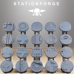 May include: A collection of gray, circular miniature bases with various industrial designs. The bases feature textures like grates, hatches, and mechanical details. The text "STATIONFORGE" and a skull logo are at the top.