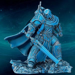 May include: A blue figurine of a warrior in ornate armor, holding a large sword. The figure has a hooded cloak and stands on a rocky base. The armor features intricate details and a skull emblem. The overall theme is fantasy or science fiction.