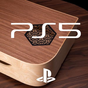 Może przedstawiać: Drewniana konsola PS5 z jasną drewnianą podstawą i ciemną drewnianą górą. Logo PS5 jest wyraźnie wyświetlane na biało, wraz z czarnym geometrycznym wzorem. Logo PlayStation znajduje się na dole.