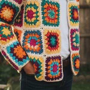 May include: A vibrant, crocheted granny square jacket. The patchwork design features squares in shades of yellow, orange, teal, purple, and pink, with a cream border. The sleeves and front panels are visible, showcasing the intricate crochet work.