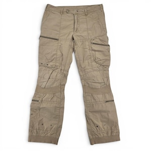 Op de afbeelding: Beige cargobroek met meerdere zakken en ritsen. De broek heeft een knoop- en ritssluiting in de taille, met versterkte knieën en enkels. De broek is gemaakt van een lichtgewicht materiaal.