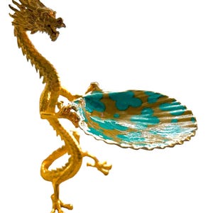 K&ouml;nnte beinhalten: Goldene Drachenfigur mit einer schalenf&ouml;rmigen Schale in T&uuml;rkis und Gold. Der Drache ist detailliert, mit langem Hals und ausgestreckten Krallen. Die Schale hat einen gewellten Rand und ein gemaltes Muster.