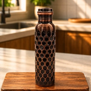 K&ouml;nnte beinhalten: Eine zylindrische Wasserflasche aus Kupfer mit einem dunklen, gepr&auml;gten Wabenmuster auf dem K&ouml;rper. Die Flasche hat einen glatten, abgerundeten Hals und einen passenden Kupferdeckel mit einem texturierten, geriffelten Rand.