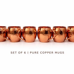 May include: Set of six pure copper mugs with a hammered finish. Each mug has a rounded body, a curved handle, and a bright copper color. The mugs are arranged in a row against a white background.