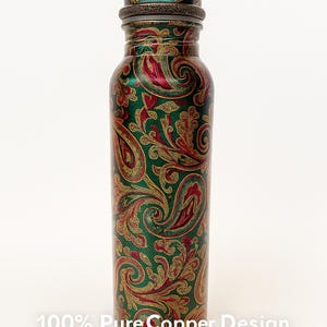 May include: A copper water bottle with a green, red, and gold paisley design. The bottle has a matching lid and is cylindrical in shape. The text "100% Pure Copper Design" and "Handcrafted Design" are visible.