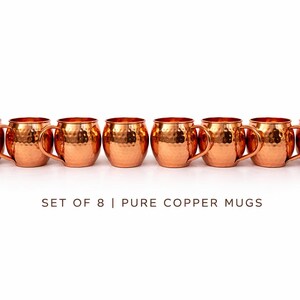 May include: A set of eight pure copper mugs with a hammered finish. Each mug has a rounded body, a curved handle, and a bright copper color. The text "SET OF 8 | PURE COPPER MUGS" is below the mugs.
