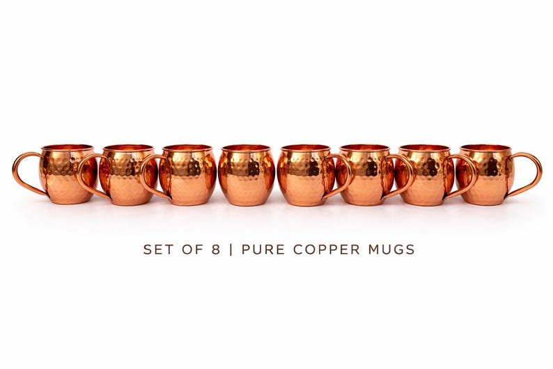 May include: A set of eight pure copper mugs with a hammered finish. Each mug has a rounded body, a curved handle, and a bright copper color. The text "SET OF 8 | PURE COPPER MUGS" is below the mugs.